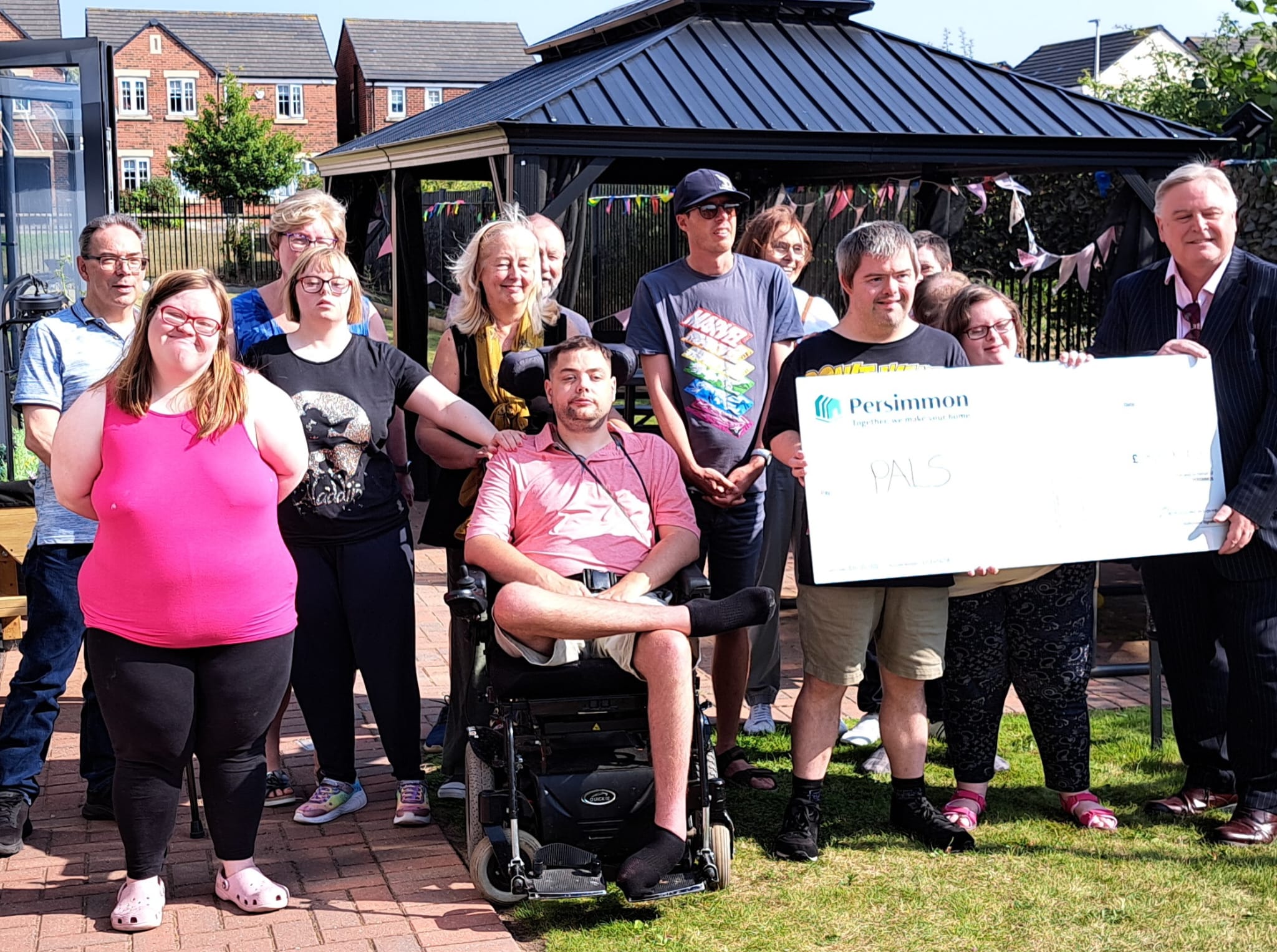 Group of people outside their house holding a cheque