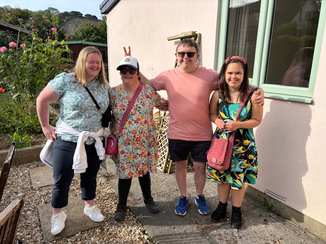 Four people standing outside their house